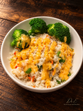 A vibrant rice-and-broccoli bowl with golden sauce, warm lighting, and a rustic wood setting. Signed Dr. E World Culture and Education.